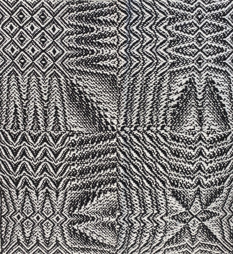 A black and white twill gamp, blocks of different twills including diamonds, zigzags and pine tree shapes meeting across the cloth